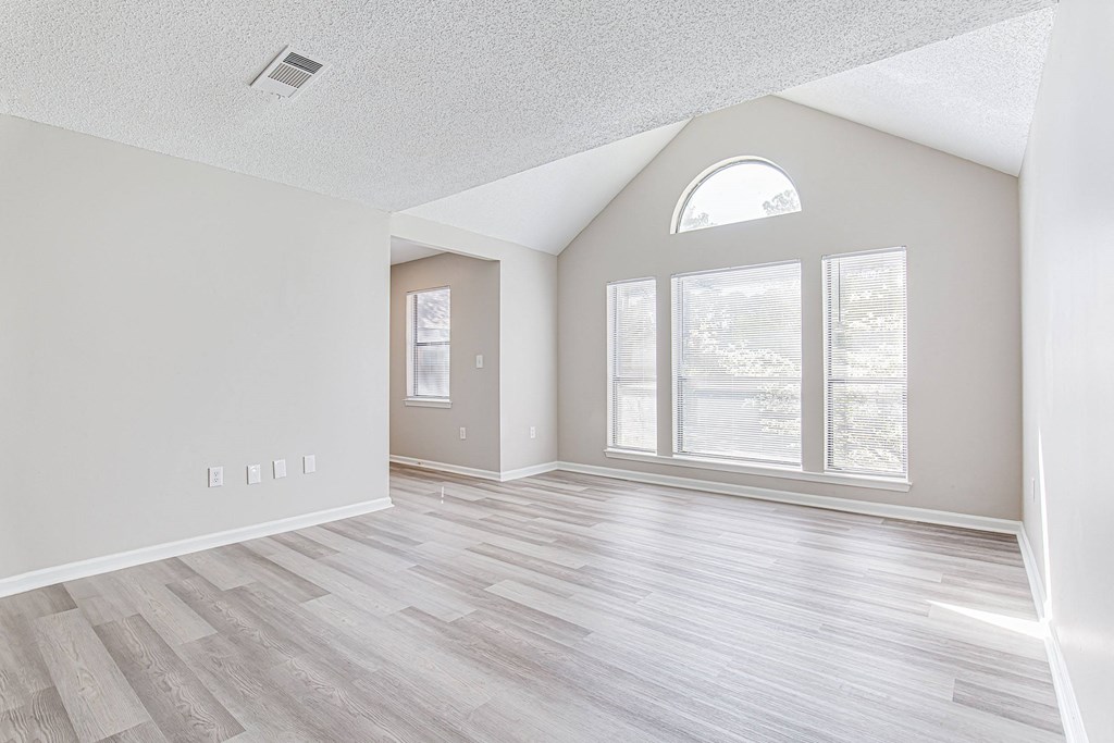 an empty living room with a large window and wooden floors