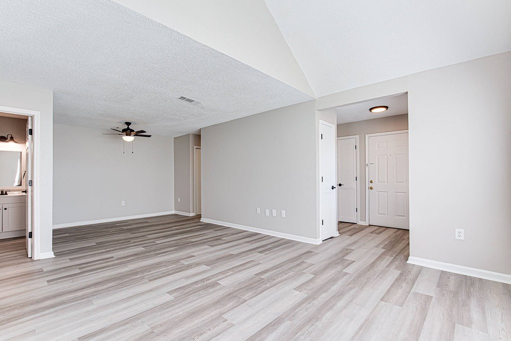 an empty living room with wood flooring and a ceiling fan