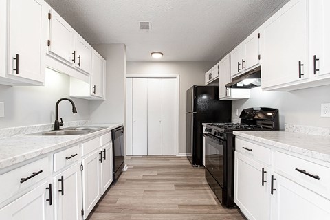 Galley kitchen with white cabinets and black appliances at Salem Glen Apartments, Conyers, Georgia