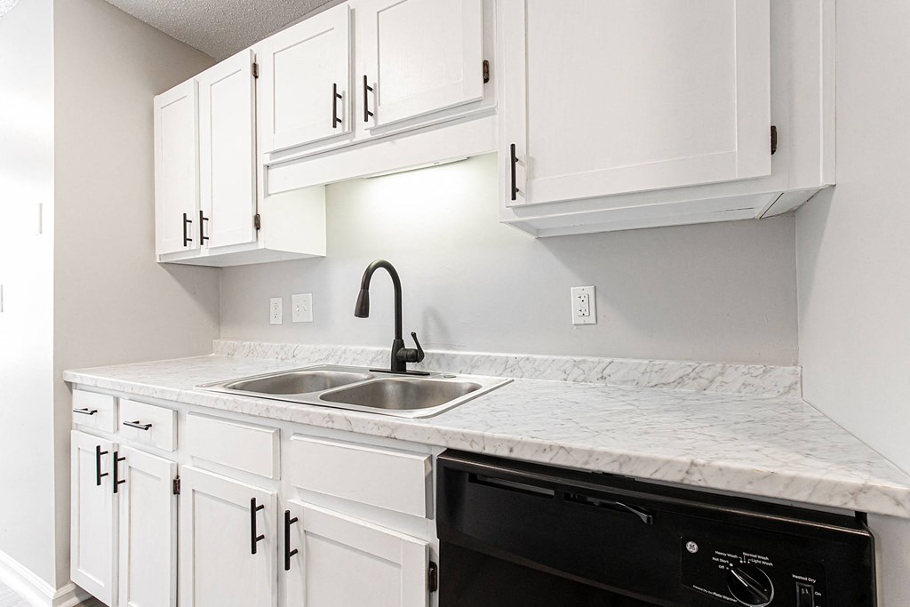 an empty kitchen with white cabinets and a sink