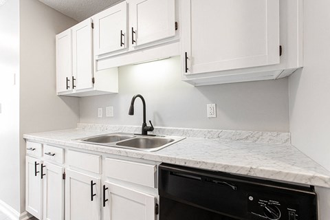 Compact kitchen with white cabinetry and marble countertops at Salem Glen Apartments, Georgia