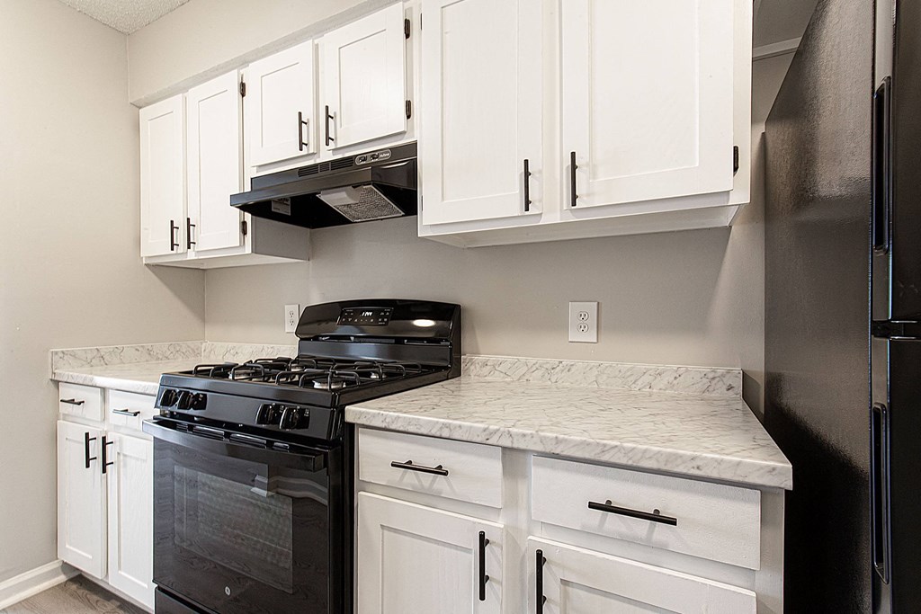 an updated kitchen with white cabinets and black appliances and a counter top with a stove