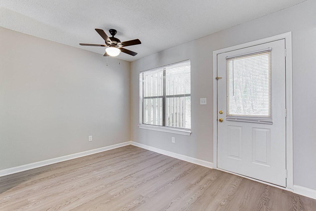 an empty bedroom with a ceiling fan and window
