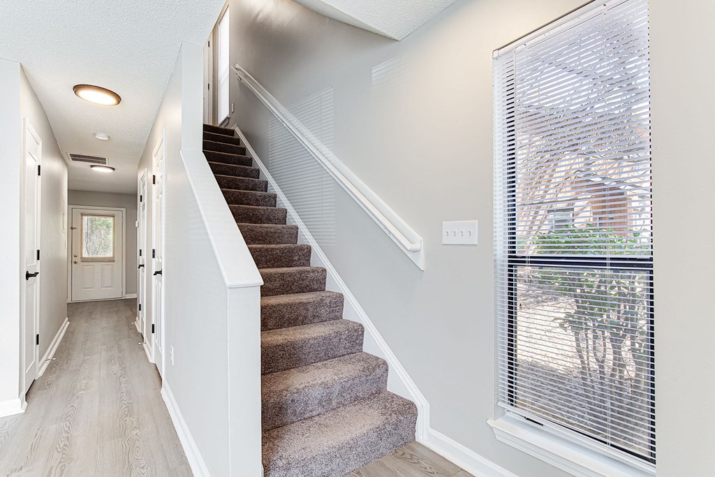 the entryway of a house with stairs and a large window