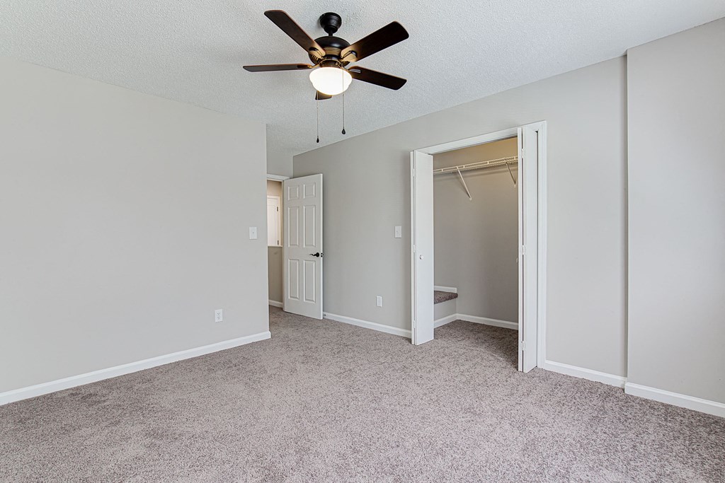 an empty bedroom with a ceiling fan and a closet