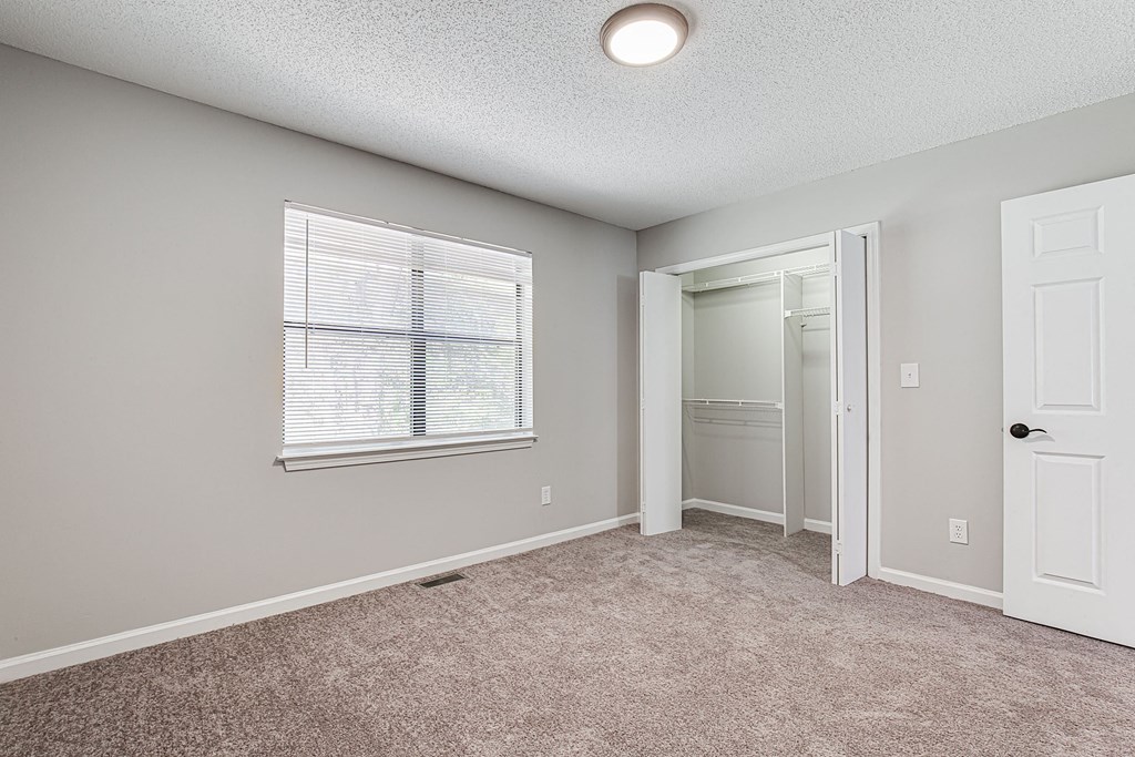an empty bedroom with a door to a closet and a window