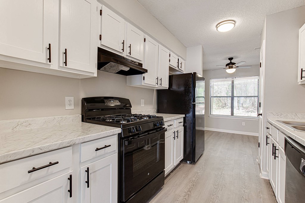 an updated kitchen with white cabinets and black appliances