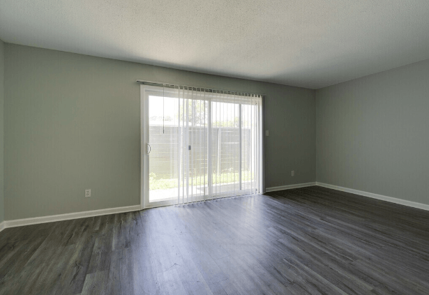 an empty living room with wood floors and a sliding glass door at Crescent Place Apartments, Georgia