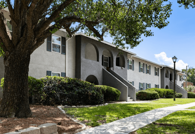 an apartment building with a sidewalk and a tree at Crescent Place Apartment, Savannah