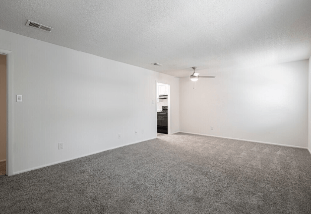 an empty living room with carpet and a ceiling fan at Crescent Place Apartments, Savannah, Georgia