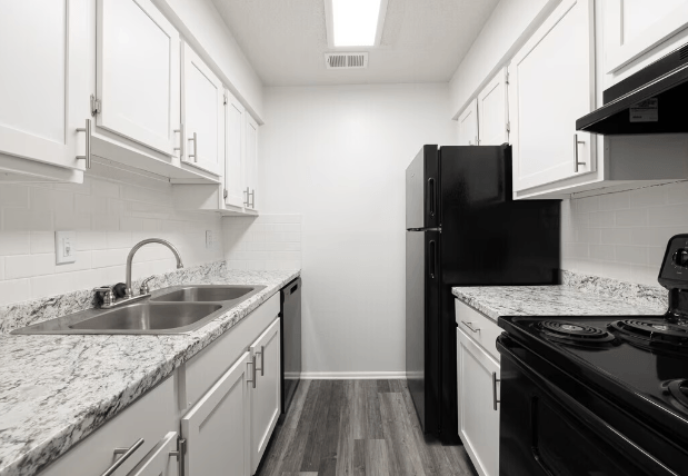 a kitchen with marble counter tops and black appliances at Crescent Place Apartments, Georgia