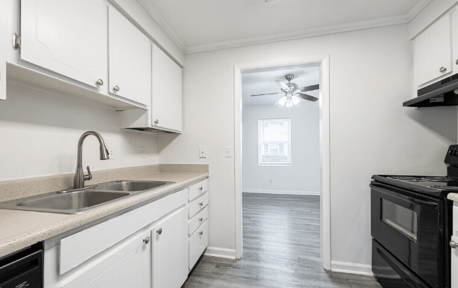 an empty kitchen with white cabinets and black appliances at Crescent Place Apartments, Savannah, GA