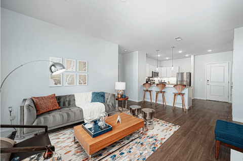 A living room with a grey couch, a wooden coffee table, and a rug with a blue cushion.