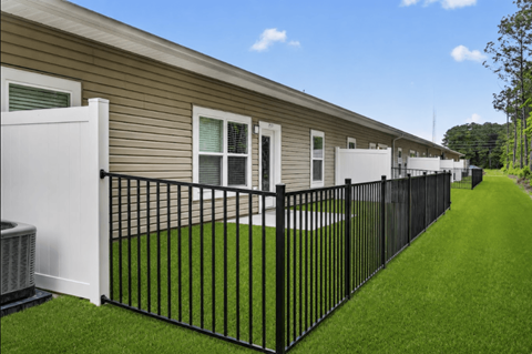 A black metal fence surrounds a grassy area in front of a building.