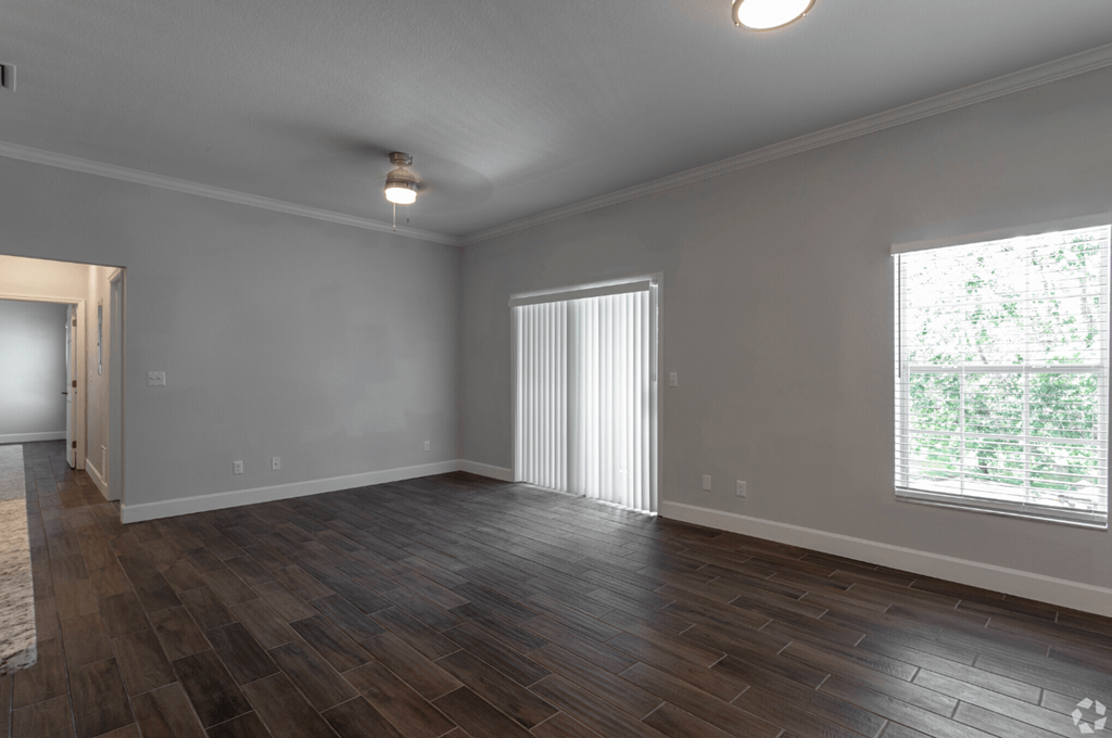 an empty living room with wood flooring and a large window an empty living room with wood flooring and a large window at Waters Edge Apartments, Lakeland, FL