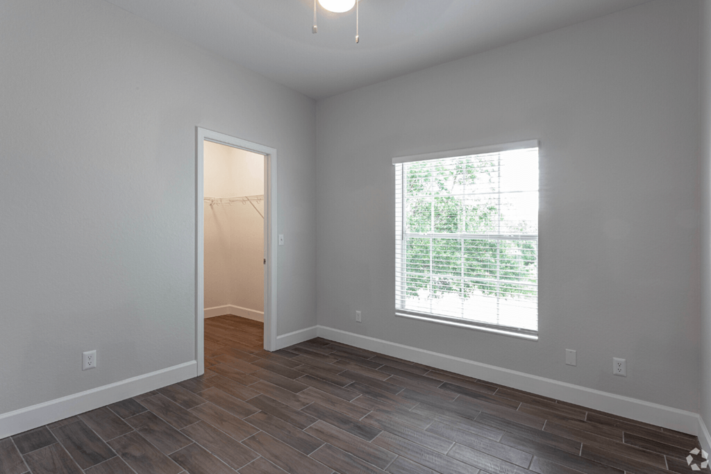 an empty room with a large window and wood flooring at Waters Edge Apartments, Lakeland, Florida