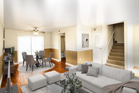 A living room with a white couch, a dining table with chairs, a rug, and a ceiling fan.