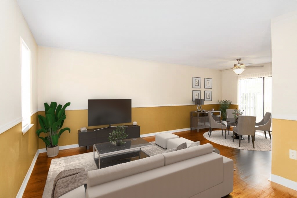 A living room with a grey sofa, a grey coffee table, a television, and a potted plant.