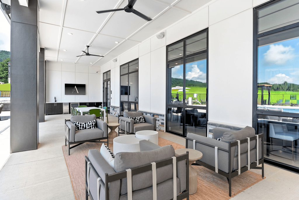 A modern living room with grey couches and a ceiling fan.