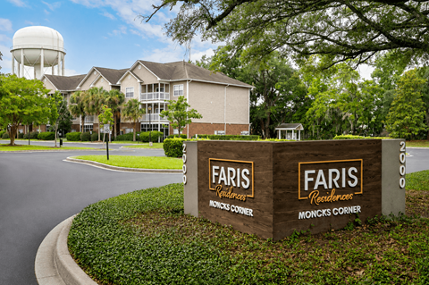 A sign for Faris Residences Moncks Corner stands in front of a building.