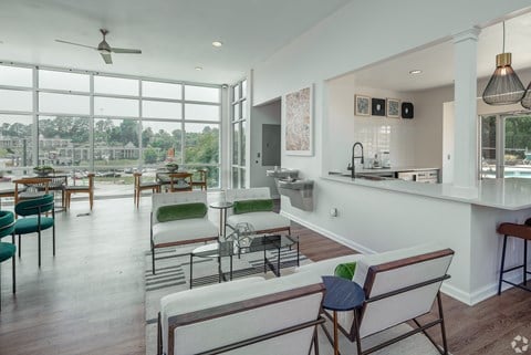 a living room with white furniture and a view of a kitchen and dining area