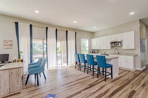 an open kitchen and dining area with blue chairs and a white kitchen island with a