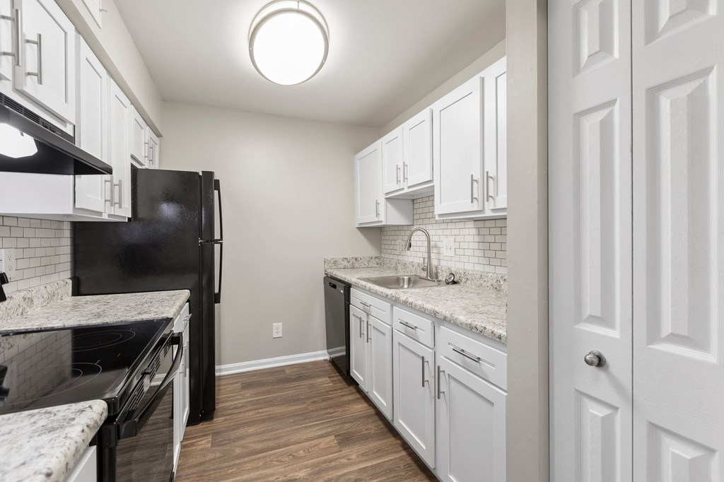 a kitchen with white cabinets and black appliances
