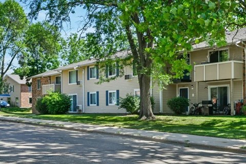 A tree in front of a building with a car parked in front of it.