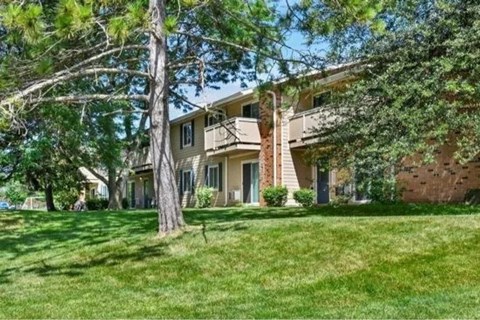 A house with a green lawn and trees in front.