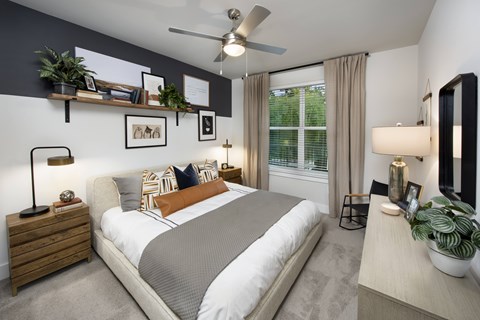 A bedroom with a large bed, a ceiling fan, and a window with curtains.