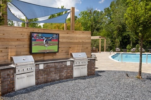 A television is mounted on a wooden wall above two grills.