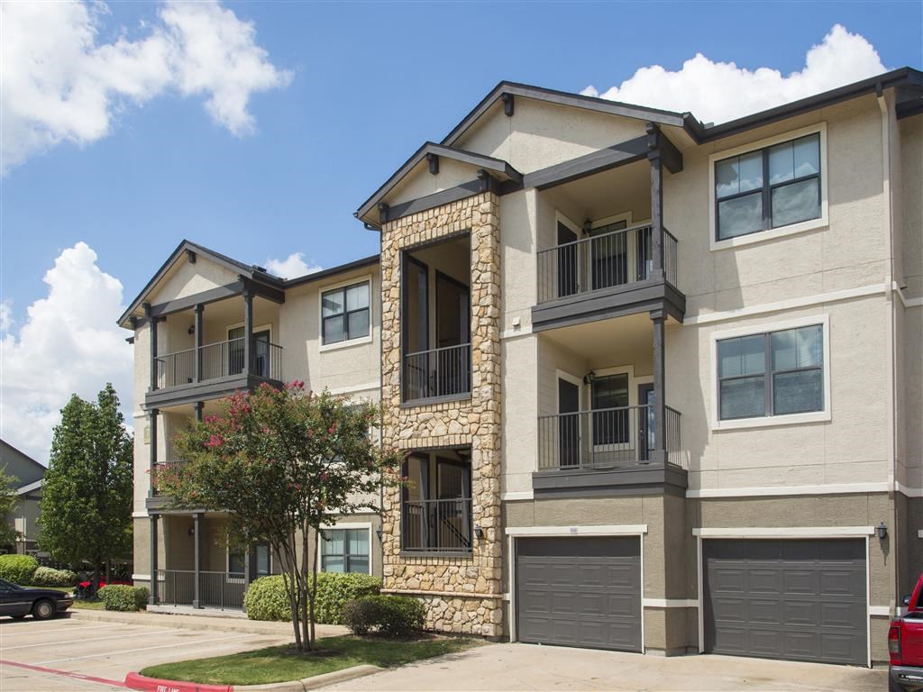 an apartment building with two cars parked in front of it
