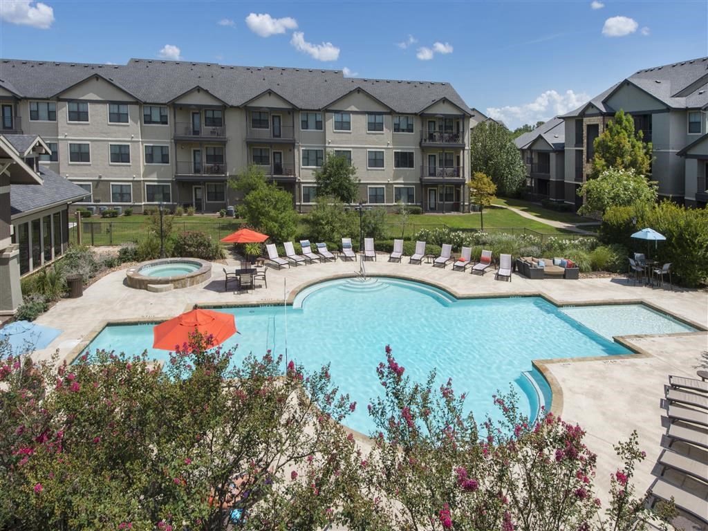 an aerial view of a swimming pool with an apartment building in the background