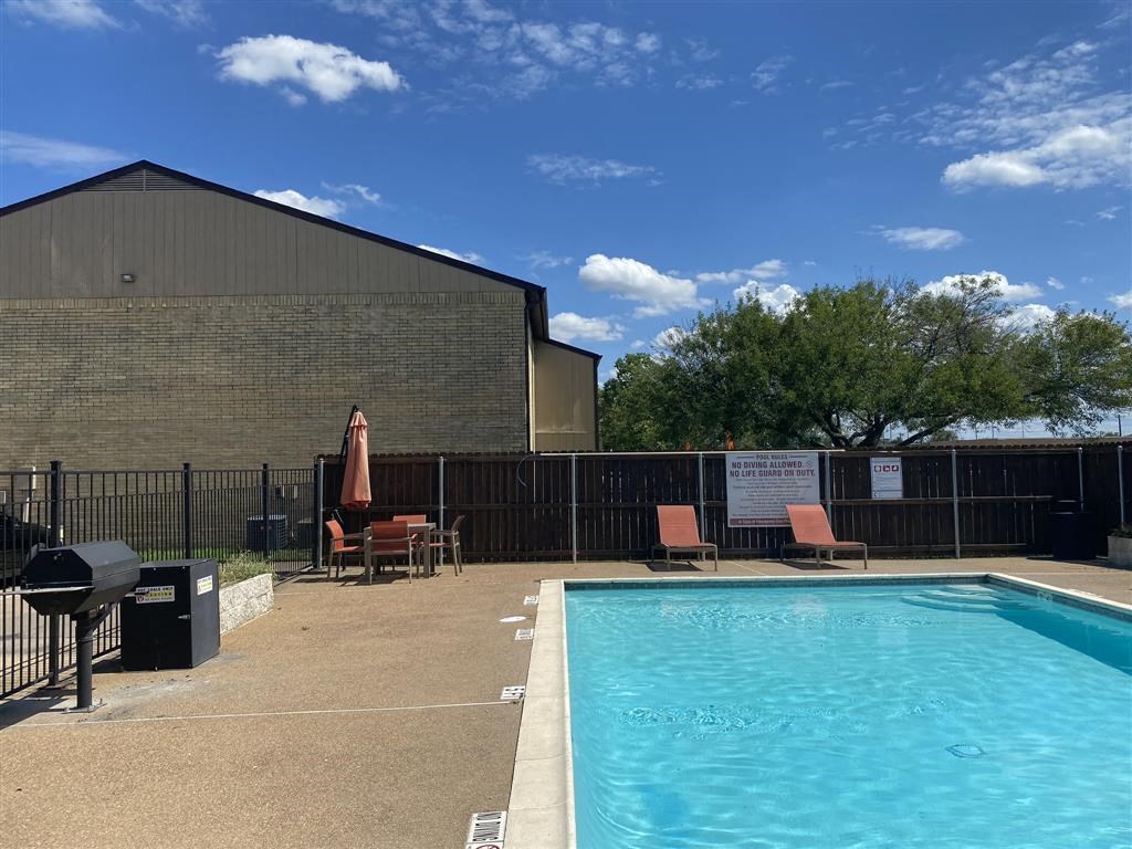 A pool area with a black fence and a building in the background.