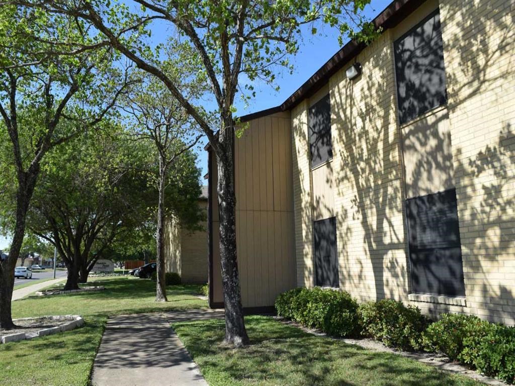 the side of a building with trees and a sidewalk