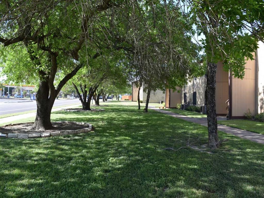 a grassy area with trees in front of a building