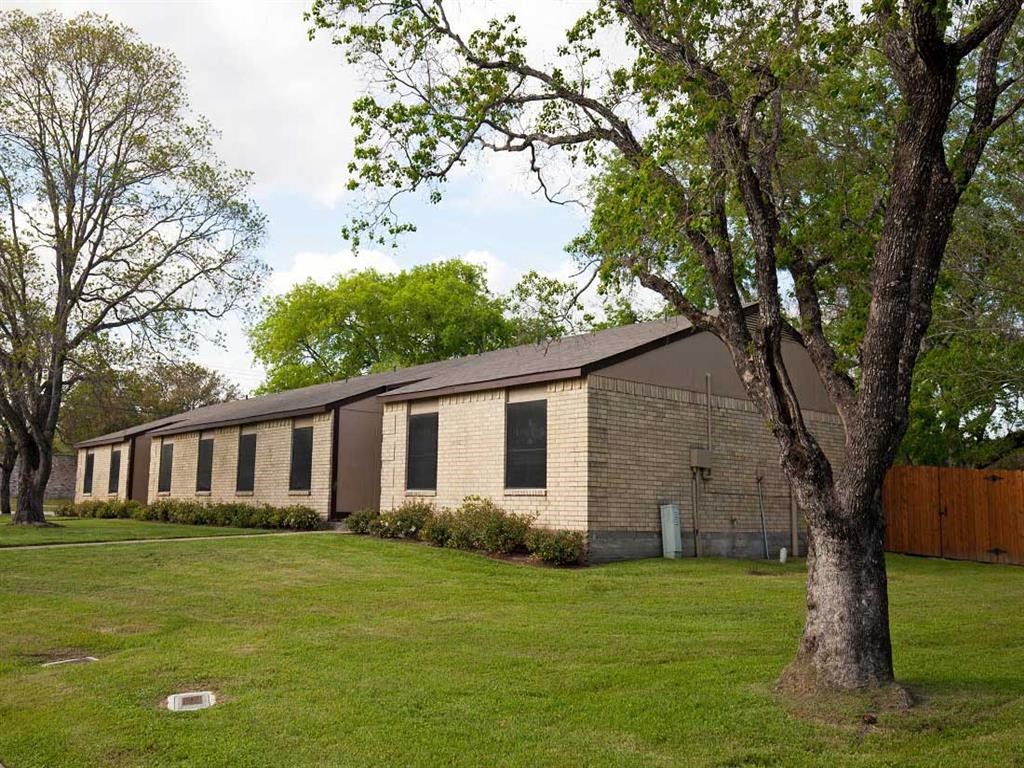 a house with a yard and trees in front of it
