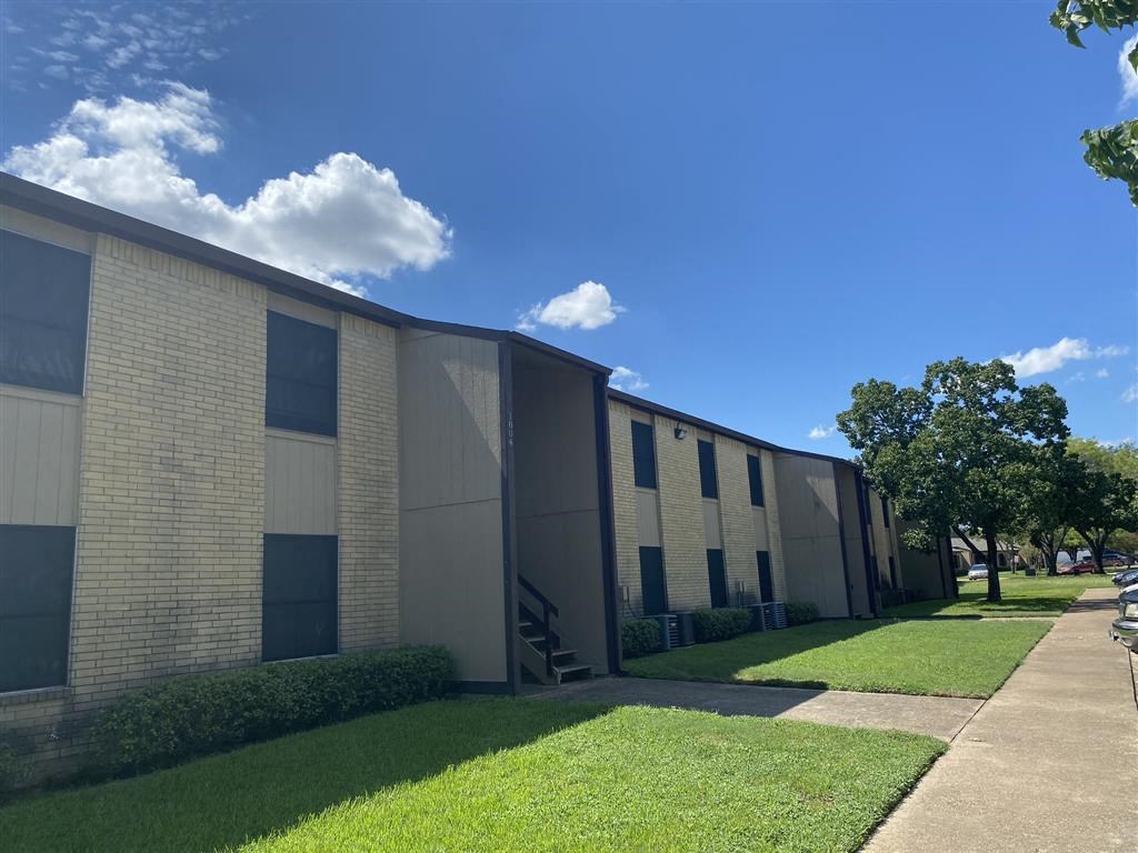 an office building with grass and trees in front of it