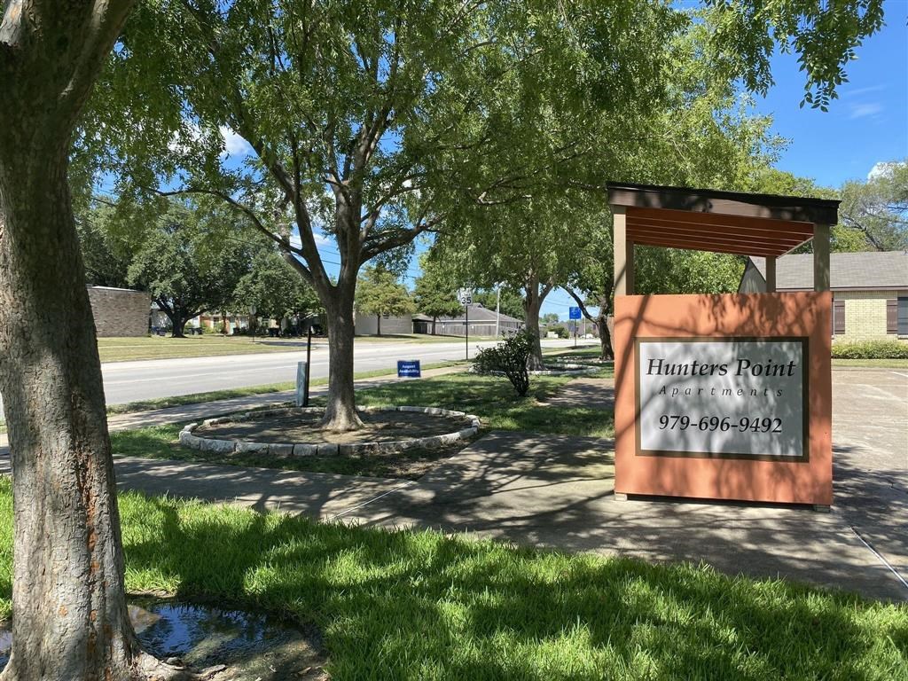 a sign in front of a park with trees