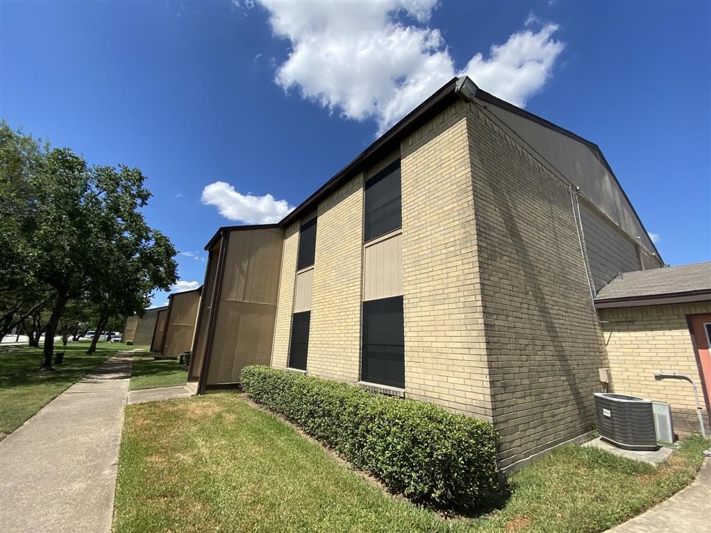 the side of a brick building with grass and a sidewalk