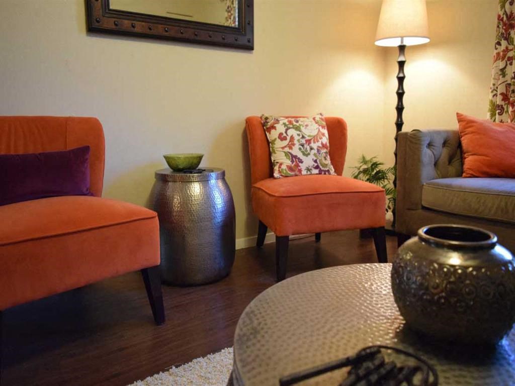 a living room with orange chairs and a table