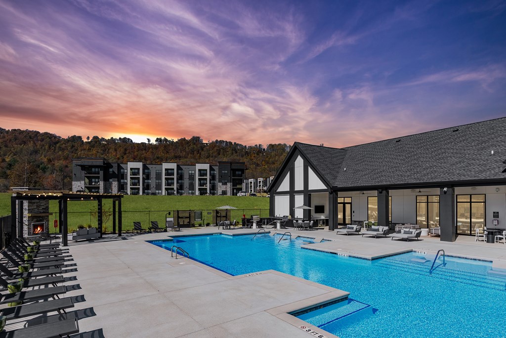 A large outdoor swimming pool with lounge chairs and a building in the background.