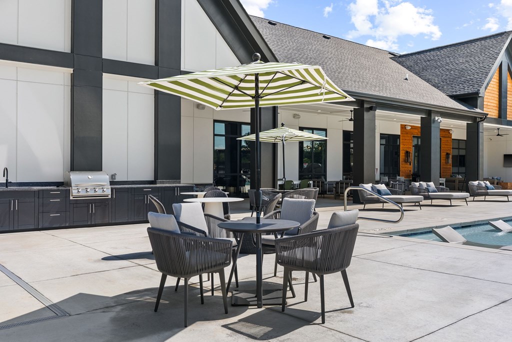 A patio with a table and chairs under a striped umbrella.