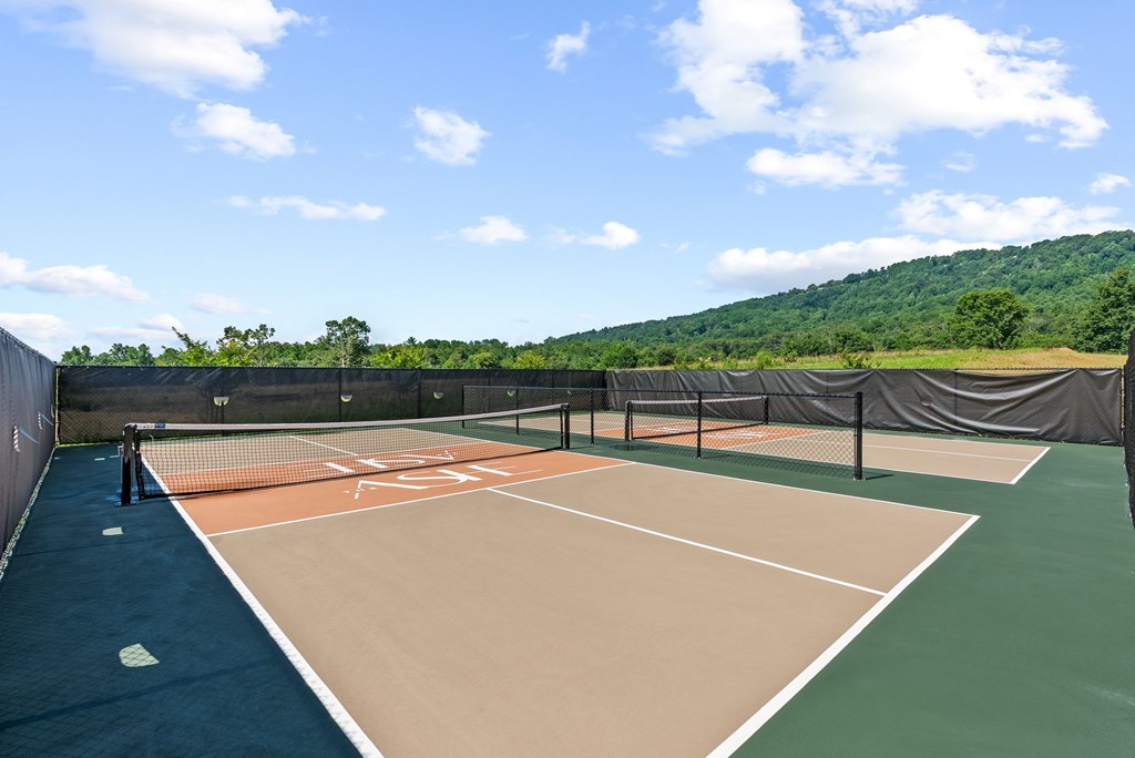 A tennis court with a blue sky and clouds in the background.
