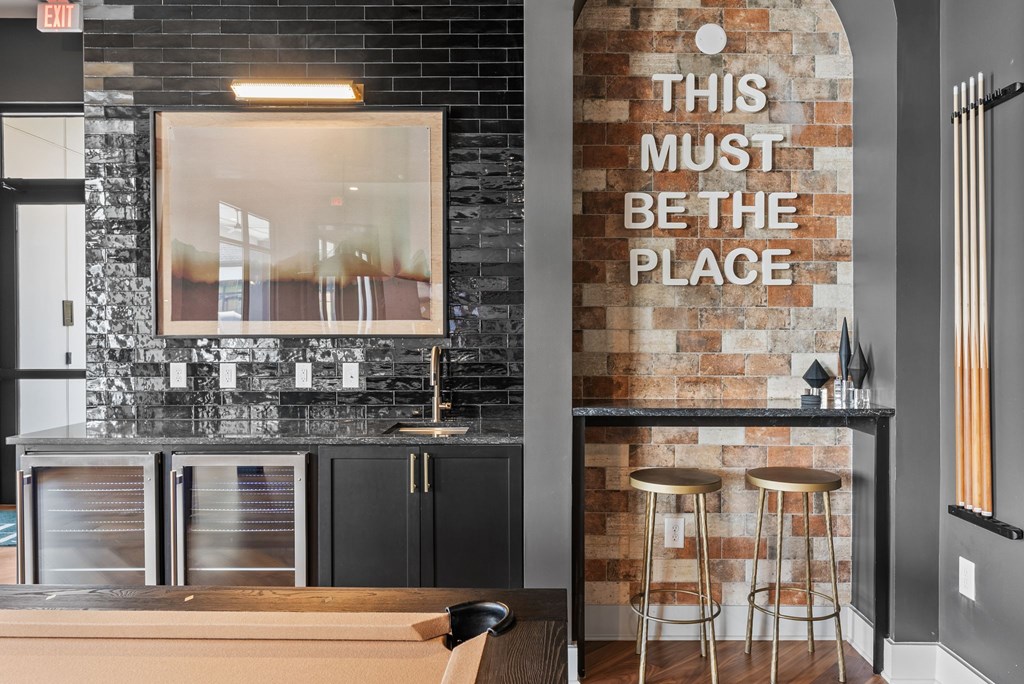 A bar area with a brick wall and a sign that says "This must be the place".