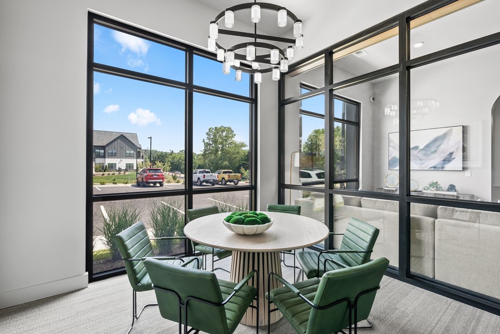 A modern dining room with a round table and green chairs.