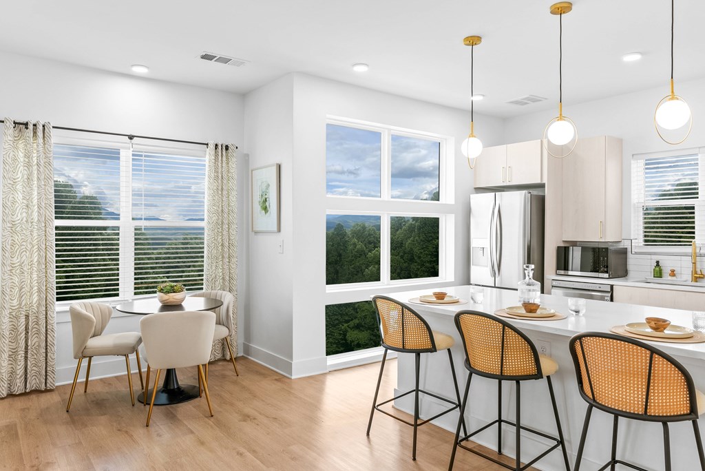A kitchen with a table and chairs in front of a window with a view of the trees.