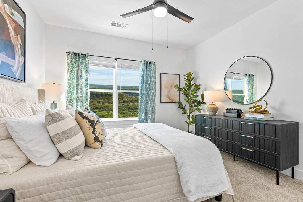 A bedroom with a large bed, a dresser, and a view of the ocean.