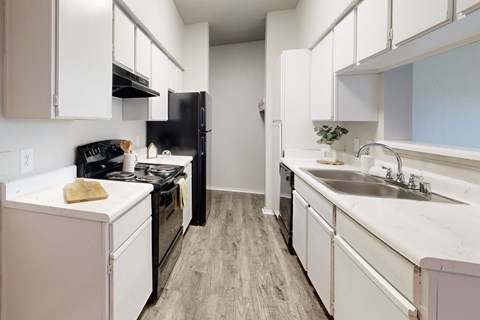 A kitchen with white cabinets and a black refrigerator.