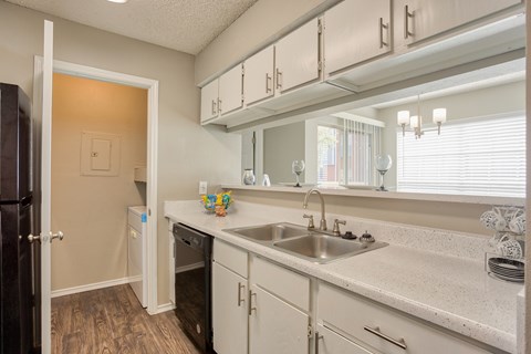A kitchen with white cabinets and a wooden floor.